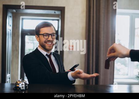 Lächelnder Geschäftsmann nimmt nach dem Einchecken im Hotel den Türschlüssel mit, selektiver Fokus. Stockfoto