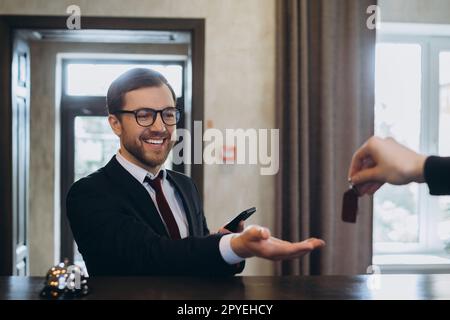 Lächelnder Geschäftsmann nimmt nach dem Einchecken im Hotel den Türschlüssel mit, selektiver Fokus. Stockfoto