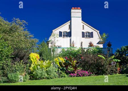 Chanticleer House, Seitenblick, Garten; 1913, antik, Weiß, schwarze Fensterläden, Kamin, grünes Gras, Sträucher, Trees, Pennsylvania; Wayne; PA; Sommer Stockfoto