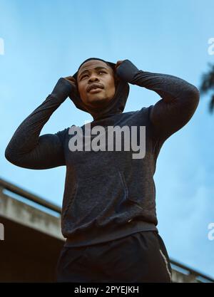 Fitness, Gesundheit und Männerläufer in einer Stadt für Training, Training und morgendliche Kardiologie vor blauem Himmel Hintergrund. Sport, Black man und entspannen Sie sich vor dem Laufen, Workout und Marathon-Training in London Stockfoto