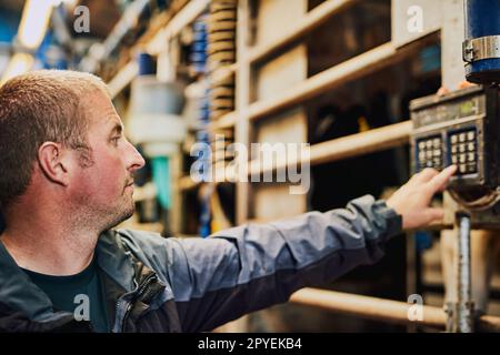 Sehen wir uns diesen Messwert an. Ein männlicher Bauer, der seine Kühe in einer Milchfabrik wiegt. Stockfoto