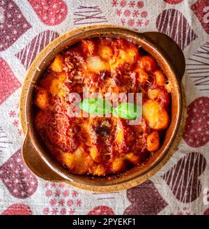 Gnocchi alla Sorrentina, italienische Kartoffelknödel in Tomatensauce, mit Mozzarella-Käse in einer Terrakotta-Schale geriebt. Stockfoto