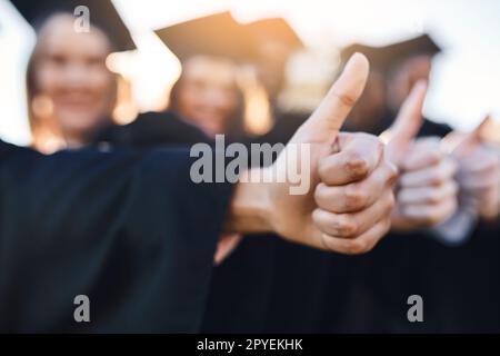 Bildung ist ein Passwort zur Freiheit. Nahaufnahme von zwei unbekannten Schülern, die am Abschlusstag Daumen hoch zeigen. Stockfoto