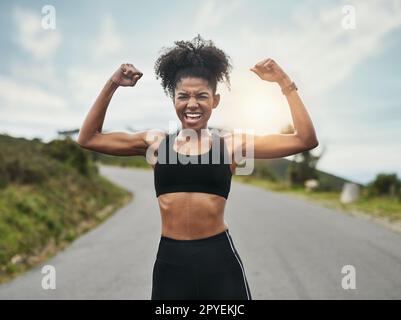 Ich bin fit und wild. Verkürztes Porträt einer attraktiven jungen Sportlerin, die ihren Bizeps nach draußen beugt. Stockfoto