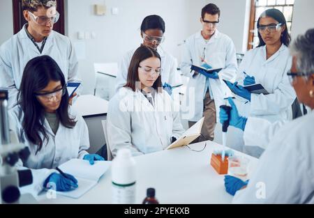 Wissenschaft, Studenten und Ausbildung in einem medizinischen Labor Schreiben Notizen während einer wissenschaftlichen Vorlesung oder Unterricht mit Mentor oder Lehrer. Medizinische Männer und Frauen für Ausbildung und Lernen im Chemiekurs Stockfoto