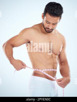 Mann, Körper oder Maßband an der Taille auf Studio Hintergrund für Gewichtsverlust Management, Fettkontrolle oder bmi Healthcare Wellness. Fitnessmodell, Sportler oder Trainer mit Maßband für Muskelziele Stockfoto