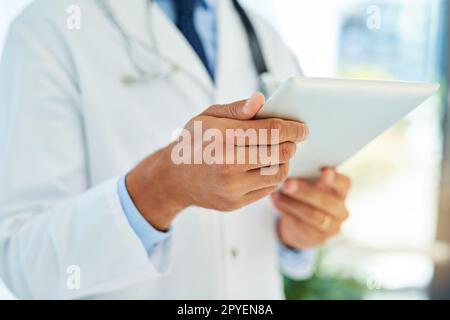 Überprüfen der Patientendateien unterwegs. Ein nicht identifizierbarer Arzt, der die Krankenakte eines Patienten auf seinem Tablet überprüft. Stockfoto