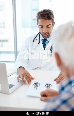 Lass mich dir das erklären. Ein gutaussehender junger Arzt, der einen Patienten in seiner Praxis berät. Stockfoto