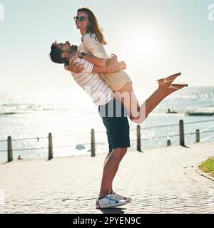 Sommerromantik-Tore. Aufnahme eines glücklichen jungen Paares in voller Länge, das einen Sommertag im Freien umarmt. Stockfoto