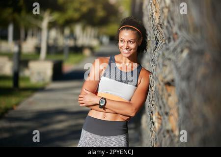 Sie hat den nächsten Abschnitt im Visier. Eine attraktive junge Frau, die eine Pause von ihrem Morgenlauf macht. Stockfoto