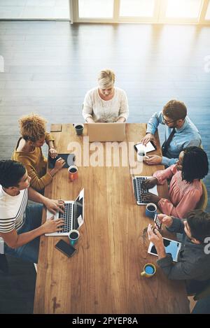 Konzentriert sich darauf, ihre Aufgaben zu erledigen. Ein Foto aus dem Blickwinkel einer Gruppe von Geschäftsleuten, die ein Meeting in einem Büro haben. Stockfoto