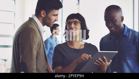 Ich hole Hilfe von ihren Kollegen. Eine Gruppe junger Designer, die sich ein digitales Tablet in ihrem Büro ansehen. Stockfoto