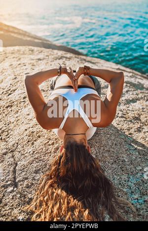 Nimm dir Zeit, um deine Seele glücklich zu machen. Eine junge Frau, die am Strand Yoga praktiziert. Stockfoto