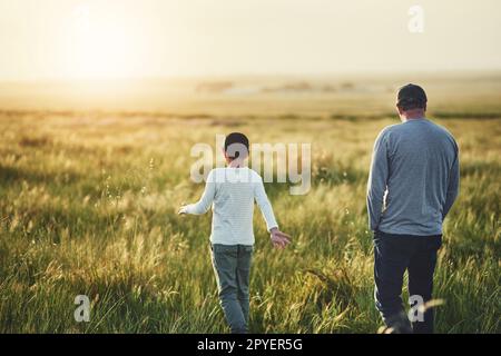 Vater-Sonne-Zeit ist unbezahlbar. Rückansicht eines Vaters und seines Sohnes auf einem Feld. Stockfoto