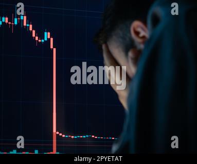 Frustrierter, depressiver Mann, der Kopf in den Händen hält, schockiert, als der globale Aktienmarkt sinkt. Stockfoto