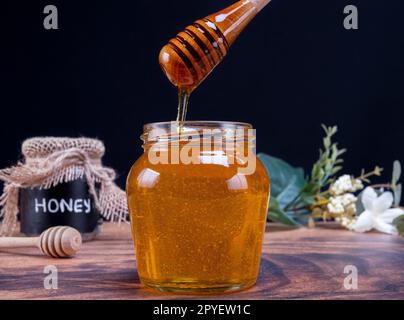 Honiglöffel, der voll Honig aus dem Glas kommt Stockfoto