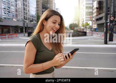 Attraktive brasilianische Frau, die ihr Handy in der Paulista Avenue, Sao Paulo, Brasilien, benutzt Stockfoto