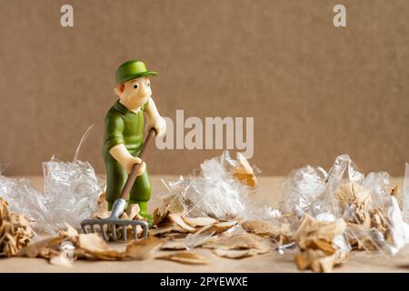 Ein Spielzeugmann im Arbeiteranzug macht eine große Menge Müll. Umweltschutz und Ökologiekonzept. Stockfoto