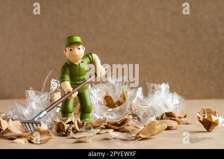 Ein Spielzeugmann im Arbeiteranzug macht eine große Menge Müll. Umweltschutz und Ökologiekonzept. Stockfoto