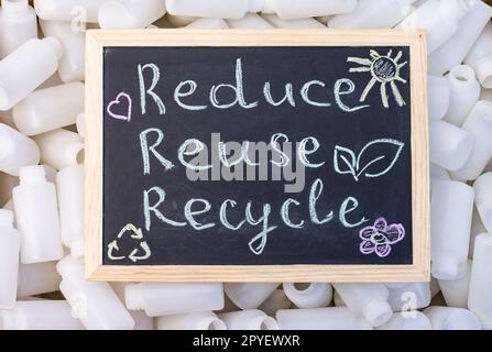 Kreidetafel REduse Recycle Schild auf dem Hintergrund leerer Kunststoffverpackungen. Draufsicht. Stockfoto