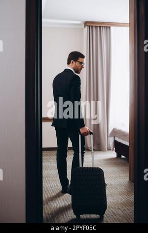 Zurück Blick auf junge elegante Business Traveler in formale Eingabe komfortable Hotel Zimmer am Morgen Stockfoto