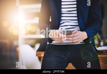 Ein Telefon, so viele Funktionen für das Geschäft. Ein Geschäftsmann, der ein Mobiltelefon in einem modernen Büro benutzt. Stockfoto