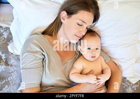 Sie schläft fest mit ihr in den Armen. Eine junge Mutter und ihr Baby zu Hause. Stockfoto