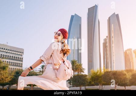 Erleben Sie die beeindruckende Schönheit der Architektur von Abu Dhabi, die sich gegen die kontrastierende Eleganz einer Frau in traditioneller indischer Kleidung richtet. Stockfoto