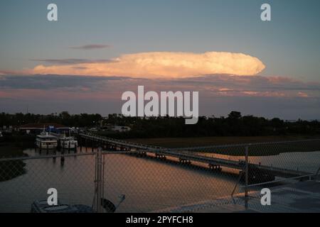 Ein malerischer Sonnenaufgang über einem ruhigen Pier, mit verschiedenen Booten, die friedlich im Wasser schwimmen Stockfoto