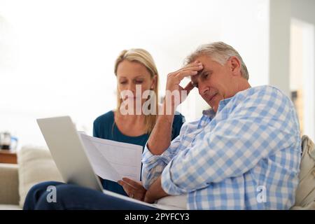 Die Lebenshaltungskosten sind heutzutage einfach zu hoch. Ein erwachsenes Paar, das gestresst aussieht, während es sein Budget zu Hause erledigt. Stockfoto