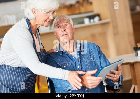 Ich zeige es dir, Liebes. Zwei leitende Geschäftsleute, die gemeinsam in ihrem Café ein Tablet suchen. Stockfoto