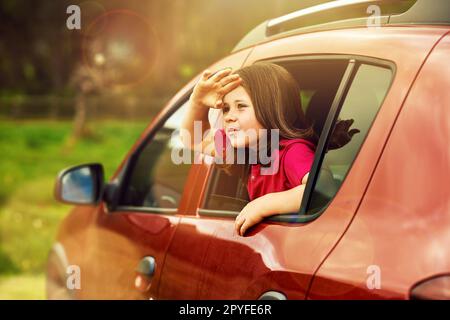 Es gibt eine ganze weite Welt zu sehen. Ein bezauberndes kleines Mädchen, das sich aus einem Autofenster lehnt. Stockfoto