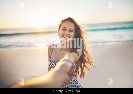 Sommer sind nur Erinnerungen, die darauf warten, wahr zu werden. Eine junge Frau zieht am Strand jemandem die Hand. Stockfoto