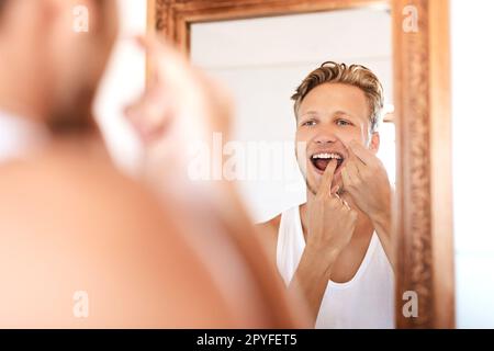 Pass auf deine kostbaren Zähne auf. Ein junger Mann, der zu Hause Zahnseide benutzt. Stockfoto