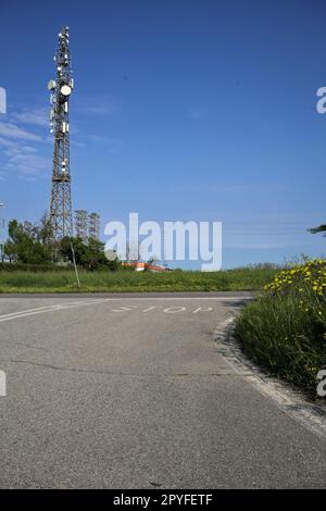 Kreuzung auf einer Landstraße mit einem Feld und einer Radioantenne in einer Umspannstation an einem sonnigen Tag Stockfoto
