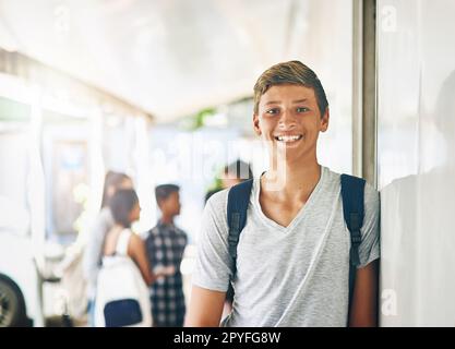 Ich will Lehrer werden, wenn ich groß bin. Porträt eines glücklichen Schuljungen, der vor seinem Klassenzimmer steht, mit Klassenkameraden im Hintergrund. Stockfoto