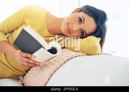 Lesen ist etwas, was man tun muss. Eine junge Frau liest ein Buch, während sie sich zu Hause entspannt. Stockfoto