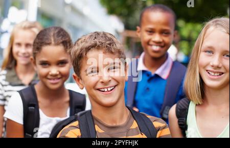 Tolle Freundschaften in der Schule aufbauen. Lächelnde Gruppe von Kindern verschiedener ethnischer Gruppen, die sich draußen für ein glückliches Bild posieren. Stockfoto