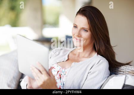 Ich Frage mich, ob sie sich am Ende treffen werden Eine attraktive Frau, die etwas auf ihrem E-Reader liest, während sie draußen sitzt. Stockfoto