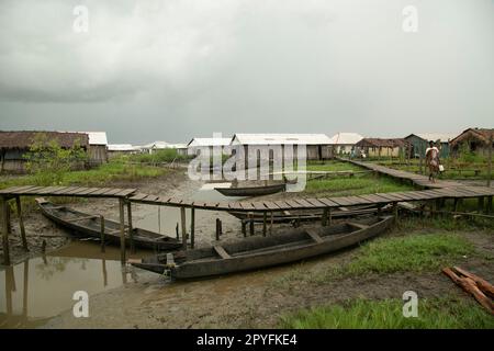 Ondo State, Nigeria - 2. Mai 2023 - Eine Frau, die auf der Holzbrücke in einer verschmutzten Umgebung der Abereke Riverine-Gegend der Ilaje-Gemeinde spaziert. Stockfoto