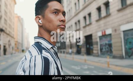 Junger Mann, der Musik hört, während er auf dem Fußgängerüberweg steht Stockfoto