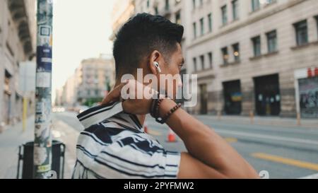 Junger Mann, der Musik hört, während er auf dem Fußgängerüberweg steht Stockfoto