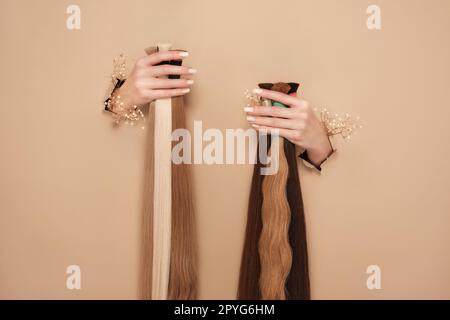 Hände mit Blumen halten Haarsträhnen für Verlängerungen auf beigefarbenem Hintergrund. Stockfoto