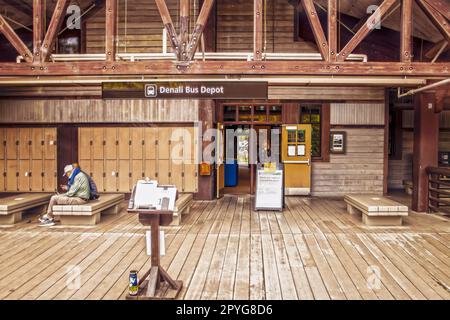 2022-06-22 Denali Alaska USA - Rustic Denali Bus Depot, wo Touristen an Bord des Busses für Touren durch den Nationalpark gehen - mit wartenden Leuten Stockfoto