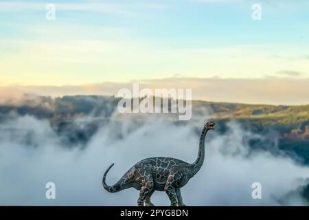 Ein Brontosaurus oder donnernder Eidechsen-Dinosaurier, der vor einem verschwommenen, nebligen Berghintergrund brüllt – geschaffen mit einem Modell vor natürlichem Hintergrund Stockfoto
