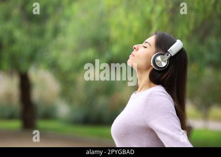 Frau, die atmet und den Audioguide in einem Park hört Stockfoto