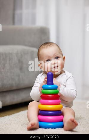 Niedliches Mädchen, das mit einer bunten Spielzeugpyramide spielt Stockfoto