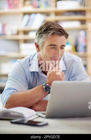 HES ist tief in das World Wide Web vertieft. Ein gut aussehender, reifer Mann, der mit einem Laptop auf dem Boden seines Wohnzimmers liegt. Stockfoto