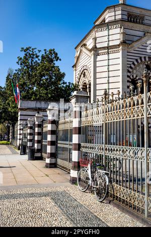 Haupteingang zum denkmalgeschützten Friedhof von Mailand, Lombardei, Italien, wo viele bemerkenswerte Menschen begraben sind, mit einem geparkten Fahrrad. Stockfoto