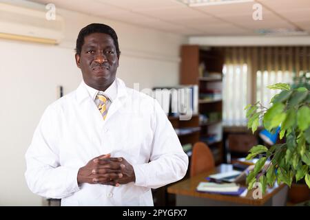 Professioneller afroamerikanischer Arzt, der im medizinischen Büro steht Stockfoto